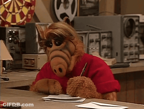 ALF Sitting At Desk With Pen GIF