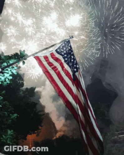 American Flag Flying In Front Of Fireworks GIF