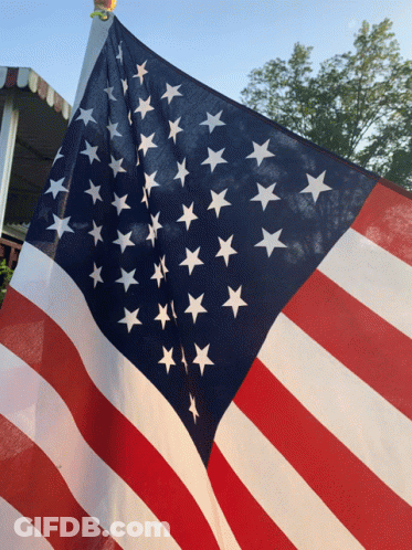 American Flag Flying In Front Of White Awning GIF
