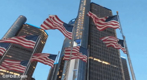 American Flags Flying In Front Of Tall Building GIF