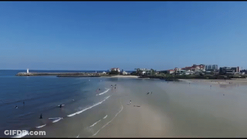 An Aerial View Of A Beach With Buildings In The Distance GIF
