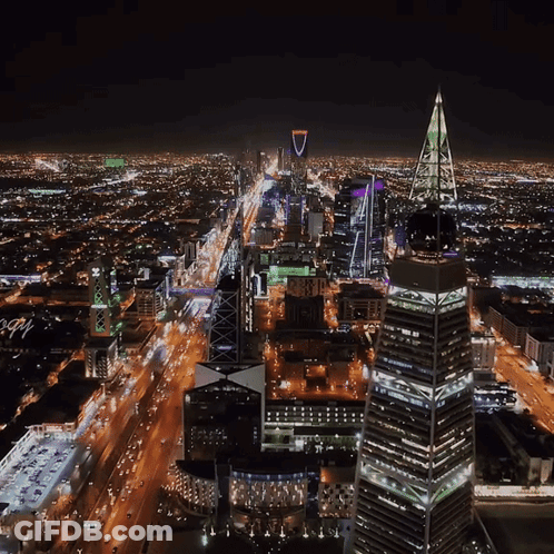An Aerial View Of A City At Night With A Tall Building In The Middle That Says ' Lbc ' On It GIF