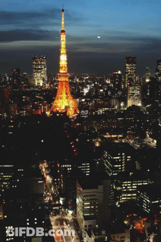 An Aerial View Of A City At Night With A Tower In The Foreground GIF