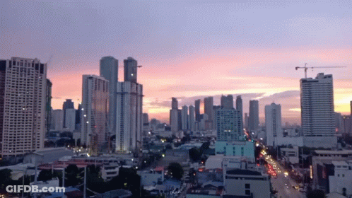 An Aerial View Of A City Skyline At Sunset With A Pink Sky In The Background GIF