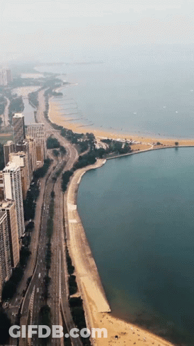 An Aerial View Of A City With A Beach And A Lake GIF