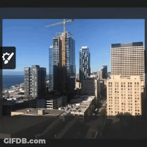 An Aerial View Of A City With A Large Crane In The Distance GIF