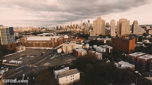 An Aerial View Of A City With A Lot Of Buildings And A Stadium In The Background GIF