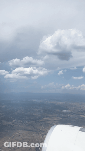 An Aerial View Of A Cloudy Sky With A Wing Of An Airplane In The Foreground GIF