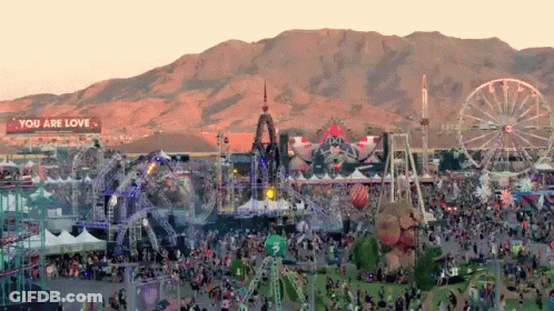 An Aerial View Of A Festival With Mountains In The Background And A Sign That Says You Are Love GIF