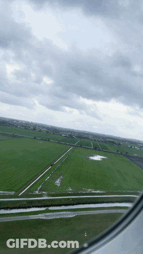 An Aerial View Of A Green Field With A Cloudy Sky GIF