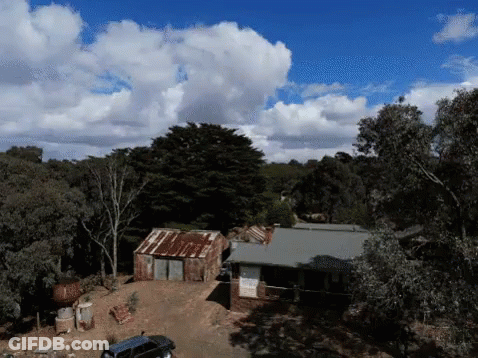 An Aerial View Of A House Surrounded By Trees And Bushes GIF
