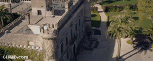 An Aerial View Of A Large Castle With Palm Trees In Front Of It GIF