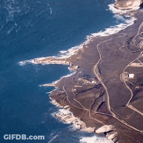 An Aerial View Of A Rocky Coastline With A Road Going Through It And A Body Of Water . GIF