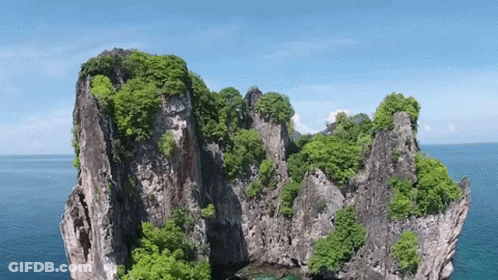 An Aerial View Of A Rocky Island In The Middle Of The Ocean . GIF