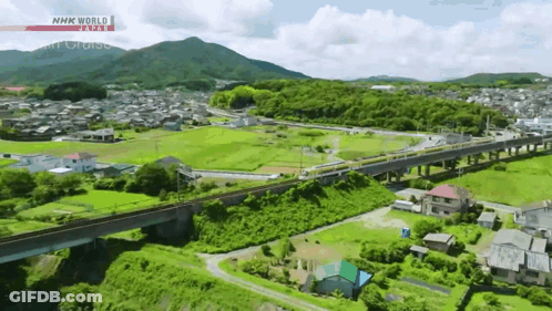 An Aerial View Of A Train Going Over A Bridge With Nhk World Written On The Bottom GIF