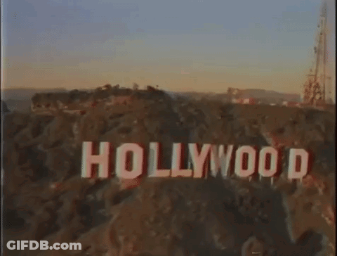 An Aerial View Of The Hollywood Sign On Top Of A Hill At Sunset . GIF