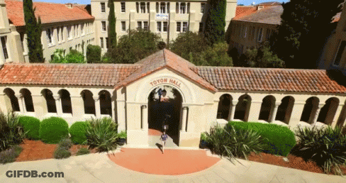 An Aerial View Of Toyen Hall With A Girl Walking Through The Entrance GIF