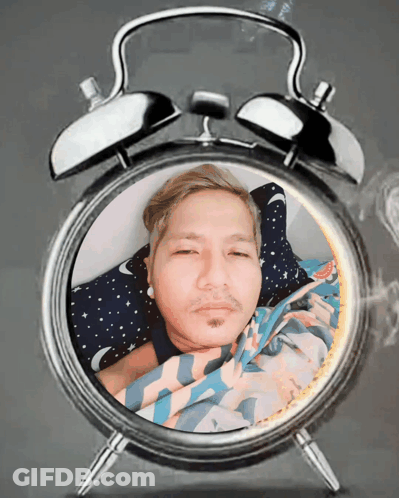 An Alarm Clock With A Man Laying In It GIF