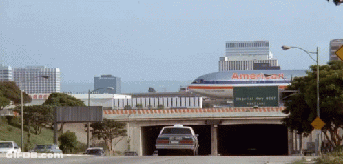 An American Airlines Airplane Is Flying Over A Highway GIF