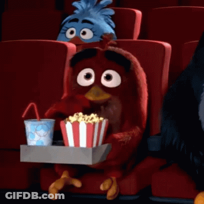 An Angry Bird Is Sitting In A Theater Holding A Tray Of Popcorn And A Cup Of Soda GIF