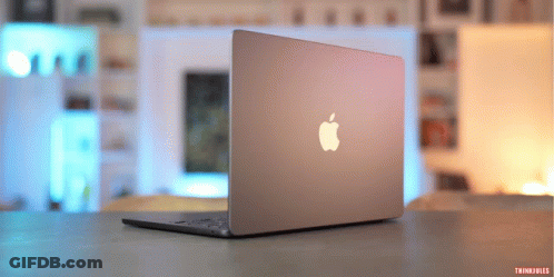 An Apple Laptop Is Sitting On A Table With A Blurred Background GIF