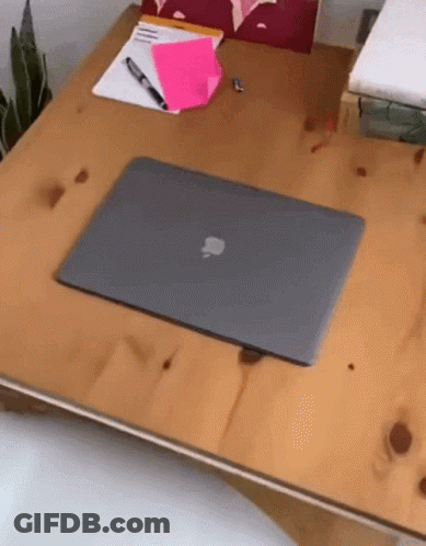 An Apple Laptop Sits On A Wooden Table GIF