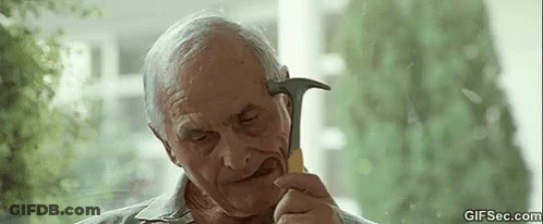 An Elderly Man Is Holding A Hammer In His Hand And Looking At It . GIF