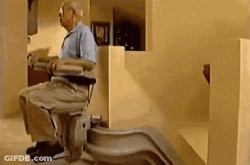 An Elderly Man Is Sitting In A Chair On A Set Of Stairs . GIF