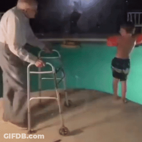An Elderly Man Is Using A Walker To Help A Young Boy Jump Into A Pool . GIF