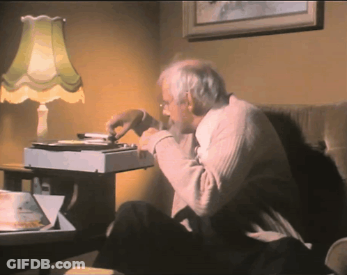 An Elderly Man Sits In A Chair Eating A Pizza GIF