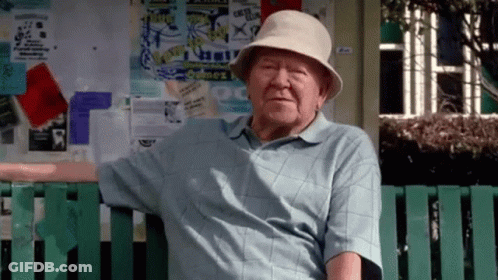 Elderly Man Sitting On Bench In Front Of Sydney Sign GIF