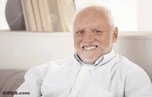 An Elderly Man With A Beard Is Smiling And Sitting On A Couch GIF