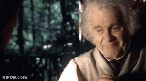 An Elderly Man With Curly Hair Is Smiling While Talking To Another Man In A Dark Room . GIF