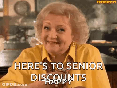 An Elderly Woman In A Yellow Shirt Is Smiling And Saying `` Here 'S To Senior Discounts Happy '' GIF