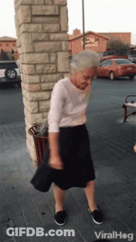 An Elderly Woman Is Dancing In Front Of A Brick Wall And A Sign That Says Viral Hog GIF