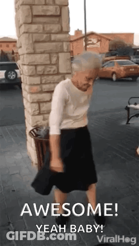 An Elderly Woman Is Dancing In Front Of A Brick Wall And A Trash Can . GIF