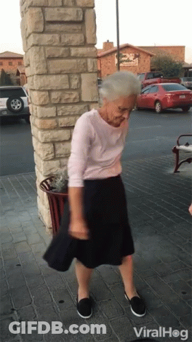 An Elderly Woman Is Dancing In Front Of A Building That Says Viral Hog GIF