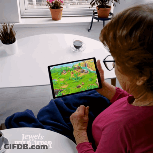 An Elderly Woman Is Playing A Game On A Tablet With The Words Jewels Of The Wild West On The Bottom GIF