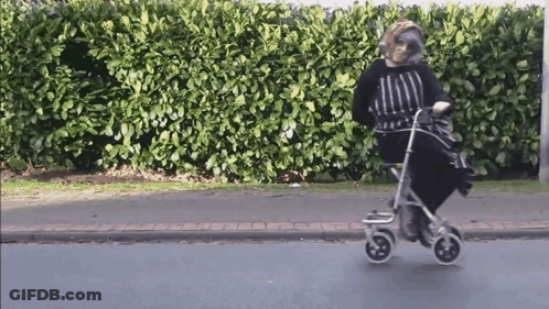 An Elderly Woman Is Riding A Walker On The Street GIF