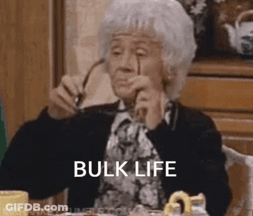 An Elderly Woman Is Sitting At A Table With Glasses In Her Hand And The Words Bulk Life Written On Her Face . GIF