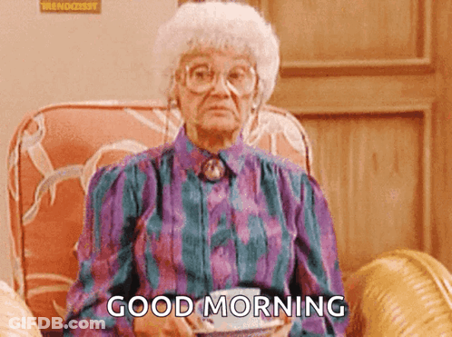 An Elderly Woman Is Sitting In A Chair Holding A Cup Of Coffee And Saying " Good Morning " GIF