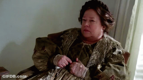 An Elderly Woman Is Sitting In A Chair With Her Hands On Her Stomach . GIF