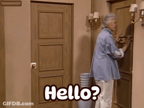 An Elderly Woman Is Standing In Front Of A Door And Says Hello GIF