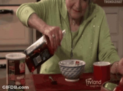 An Elderly Woman Pouring Ketchup Into A Bowl Of Cereal With A Tvland Logo On The Table GIF