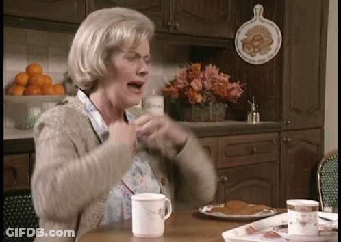 An Elderly Woman Sitting At A Table With A Cup Of Coffee GIF