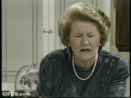 An Elderly Woman Wearing A Pearl Necklace And Earrings Makes A Funny Face GIF