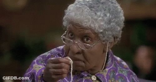 An Elderly Woman Wearing Glasses And A Wig Is Holding A Piece Of String In Her Hand . GIF