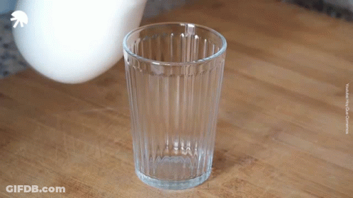 An Empty Glass Sits On A Wooden Table With A White Arrow Pointing Up GIF