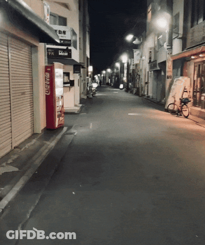An Empty Street With A Coca Cola Vending Machine On The Side GIF
