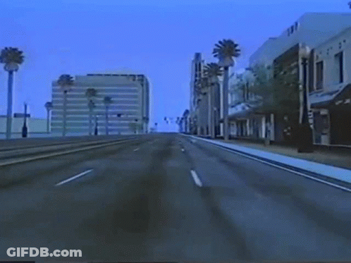 An Empty Street With Palm Trees And A Building That Says ' Tnt ' On It GIF